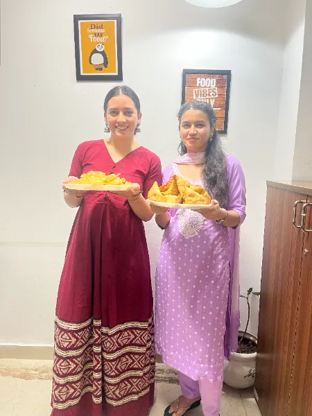 Two UIUX Studio team members serving festive sweets in the office
